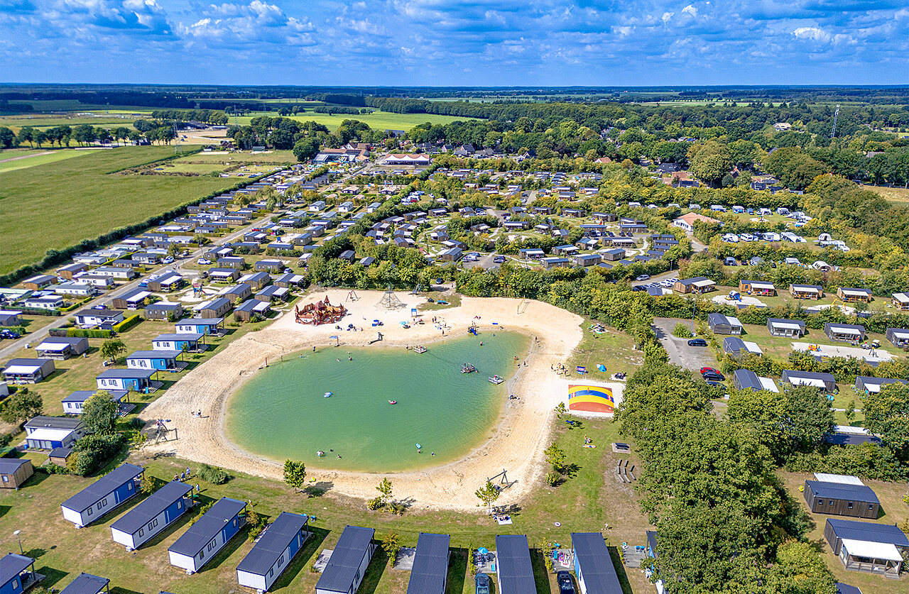 Luchtfoto zwemvijver, strand en stacaravans op camping CAPFUN De Fruithof in Klijndijk.