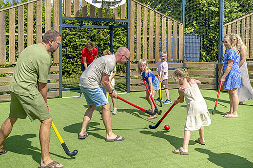 Familie speelt hockey op sportveld bij camping CAPFUN De Fruithof in Klijndijk.