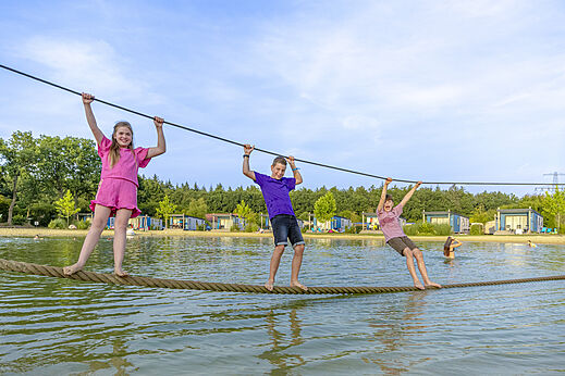 Kinderen vermaken zich op een waterparcours op camping CAPFUN De Fruithof in Klijndijk.