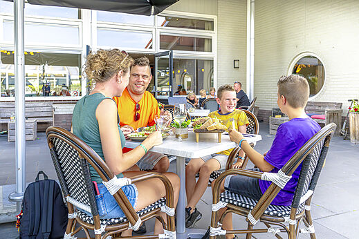 Familie dineert op het restaurantterras van camping CAPFUN De Fruithof in Klijndijk.