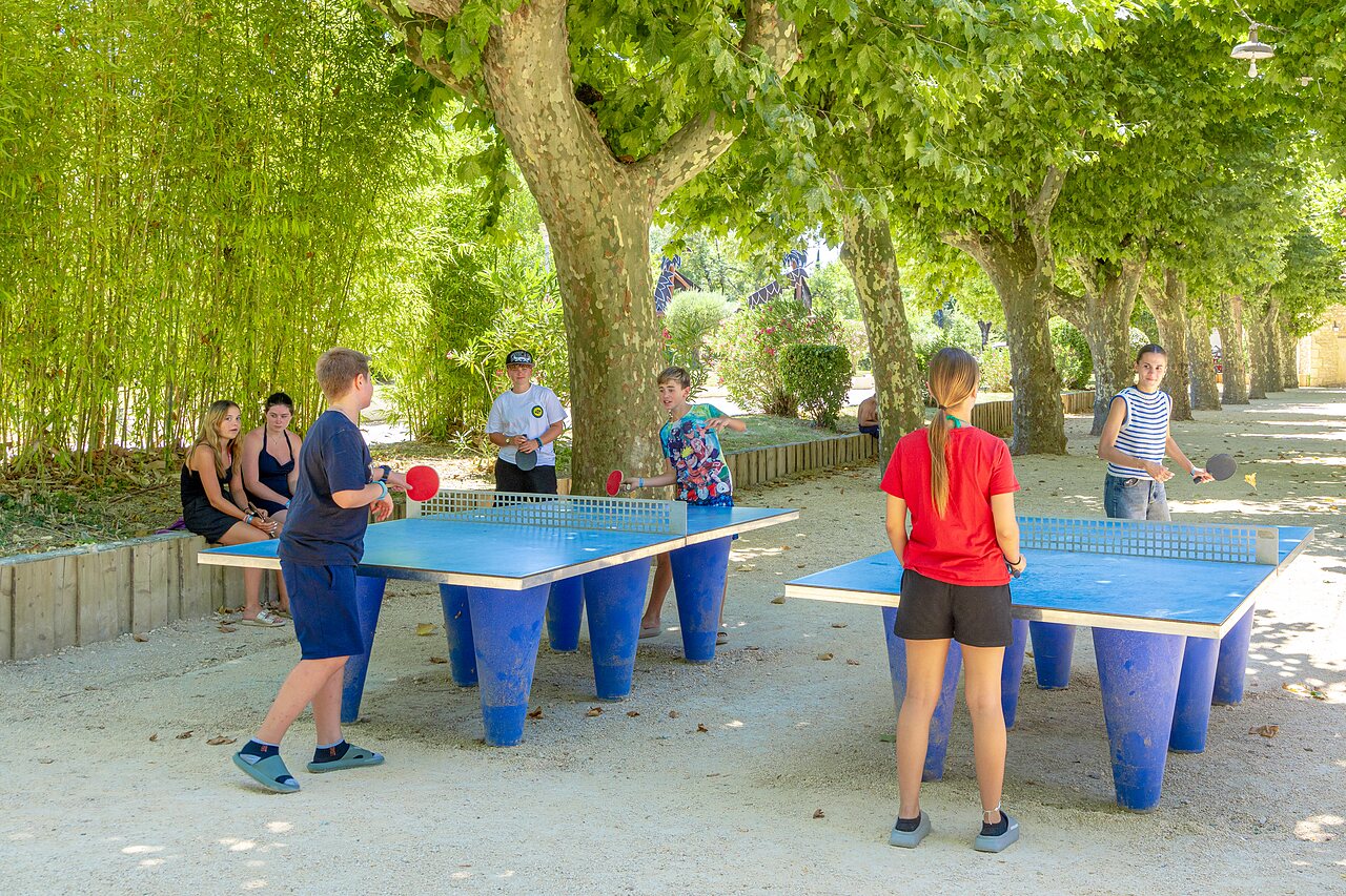 Jongeren spelen buitentafeltennis in de schaduw op camping CAPFUN Fumades.