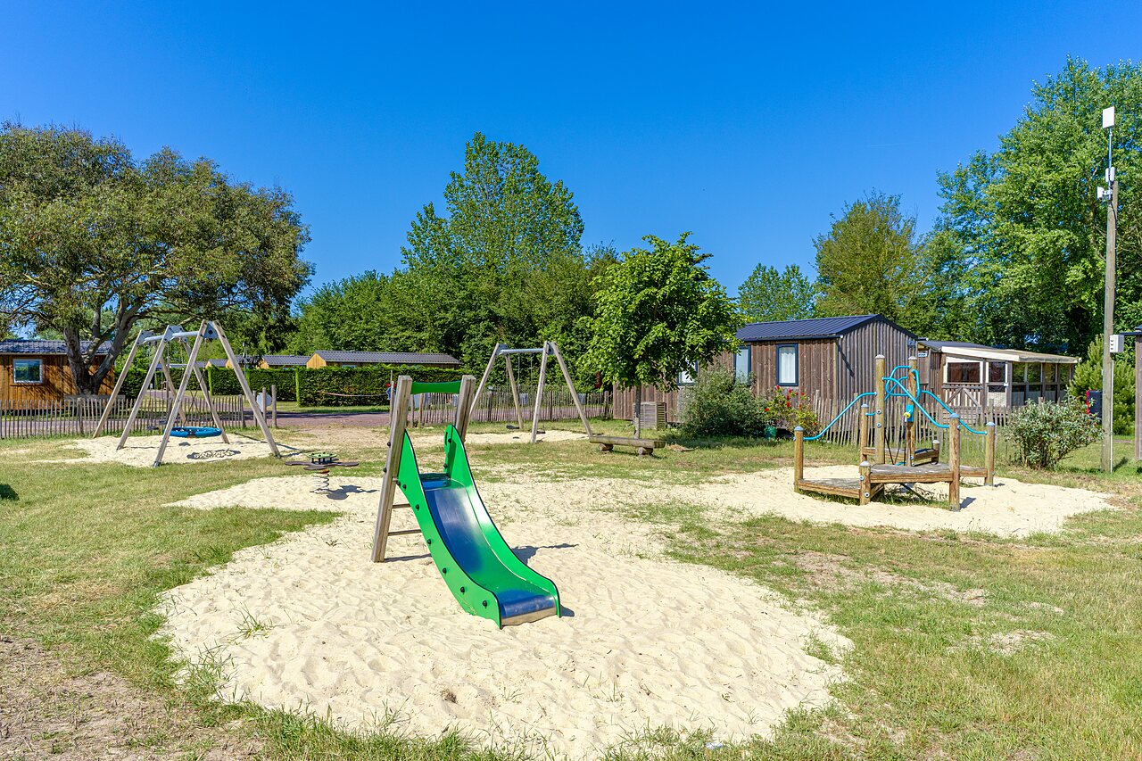 Speeltuin met glijbaan en schommels op camping CAPFUN Golf, SAINT JEAN DE LA RIVIERE (50).