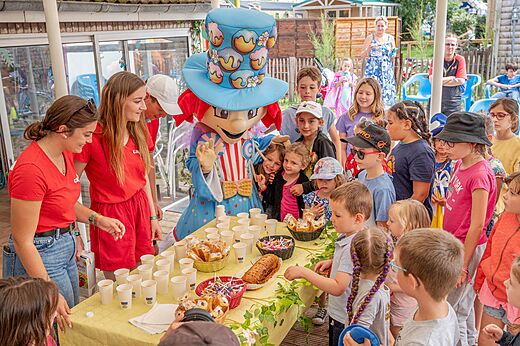 Mascotte en kinderen genieten van een snackanimatie op camping CAPFUN Golf in SAINT JEAN DE LA RIVIERE (50).