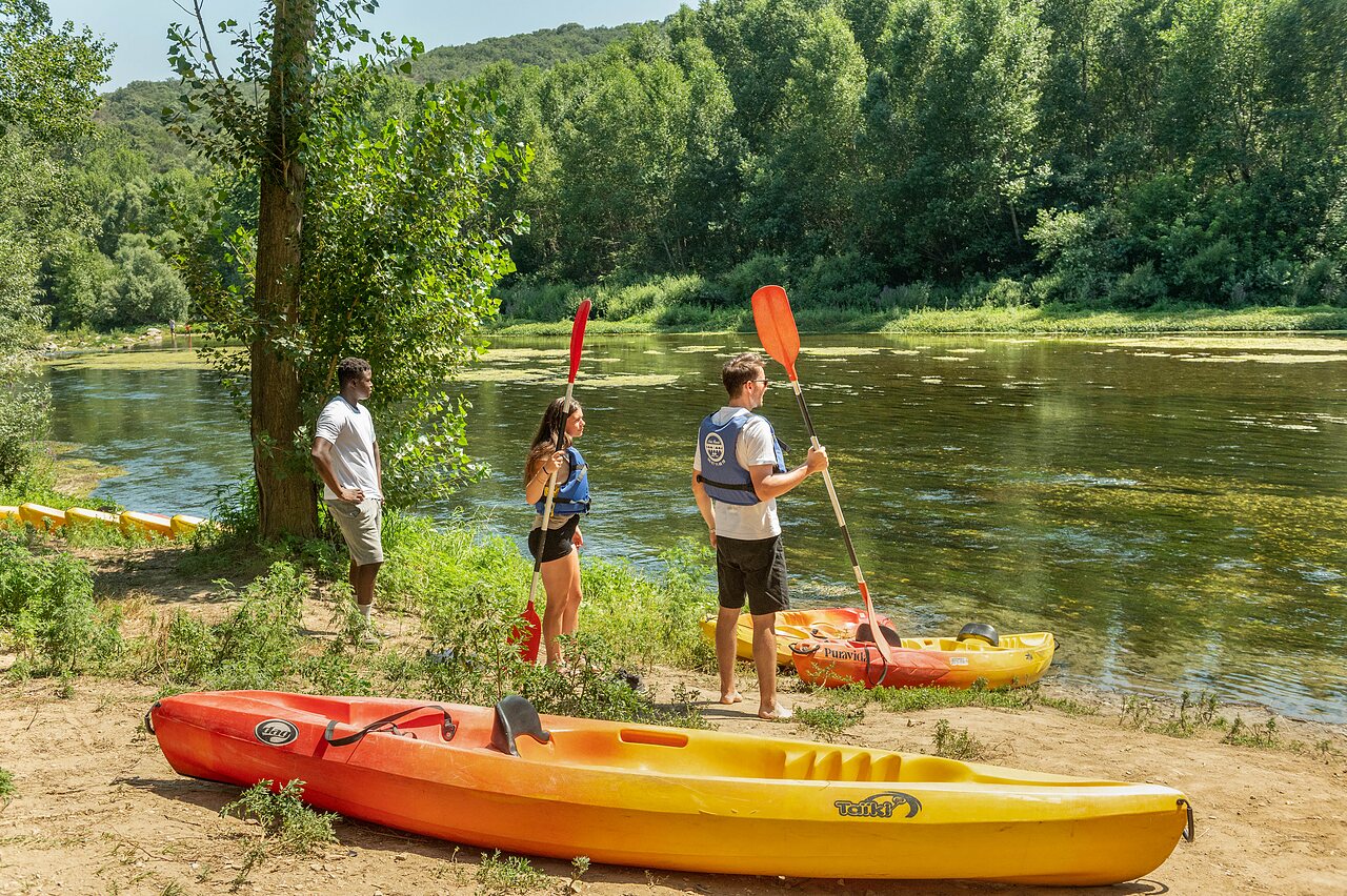 Mensen met kajaks en peddels aan de rivieroever op camping CLICOCHIC Gorges du Gardon in VERS PONT DU GARD (30).
