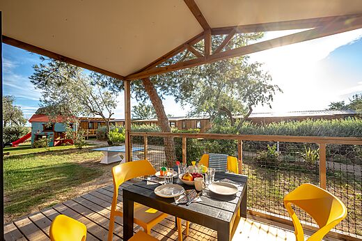 Terras van stacaravan met tafel en kinderspelen op camping CAPFUN Grande Cosse in Saint Pierre la Mer.