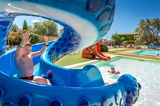 Kind op blauwe waterglijbaan en zwembad op camping CAPFUN Grande Cosse in Saint Pierre la Mer (11).