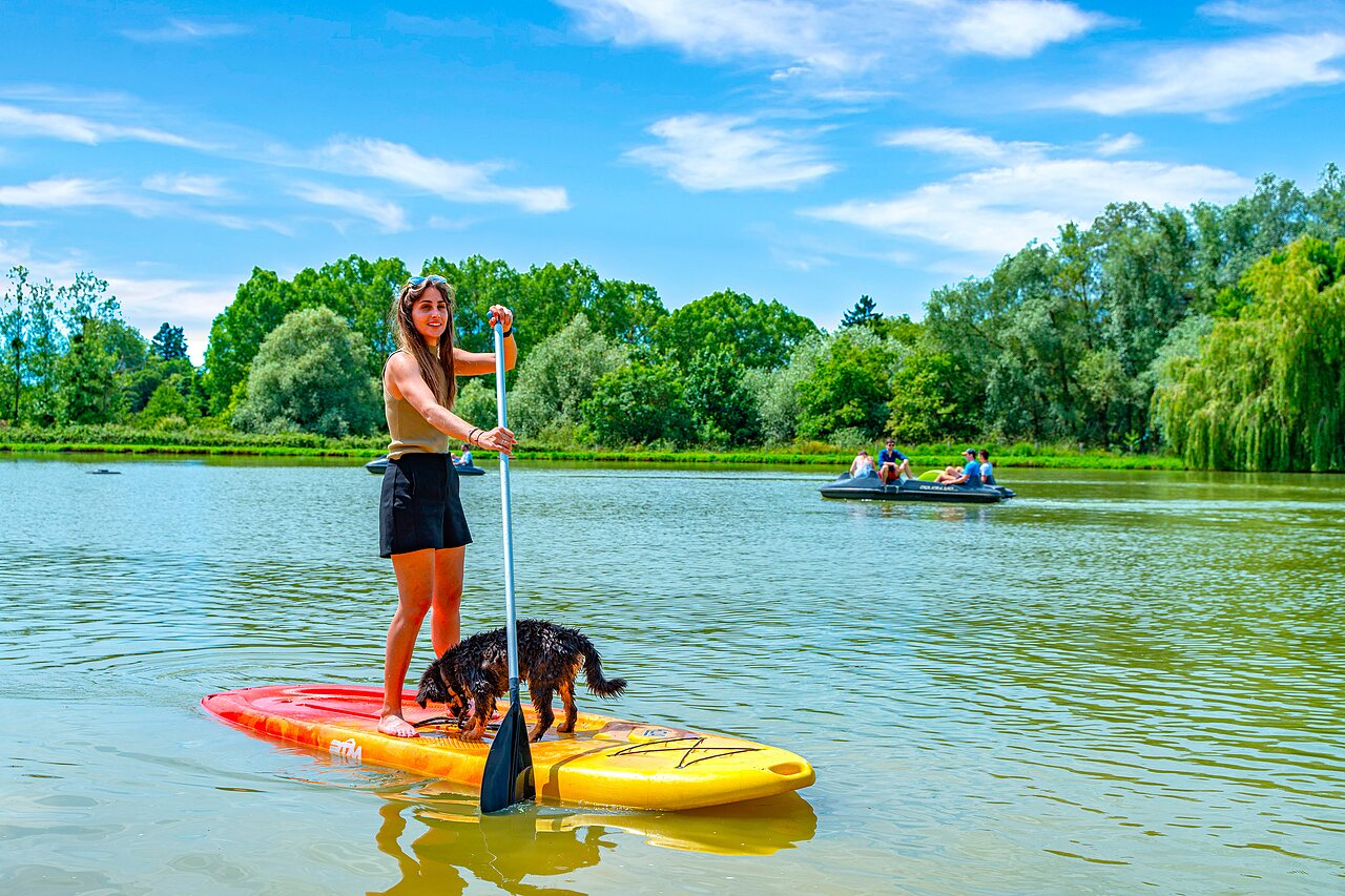 Vrouw en hond op stand-up paddleboard op het meer bij camping CAPFUN Grand Cerf in Gimouille (58).
