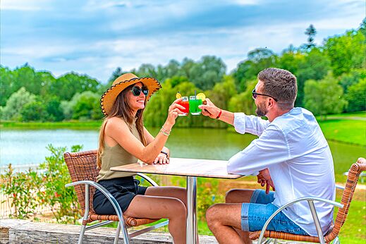 Paar proost met cocktails op het terras van de bar op camping CAPFUN Grand Cerf in Gimouille (58).