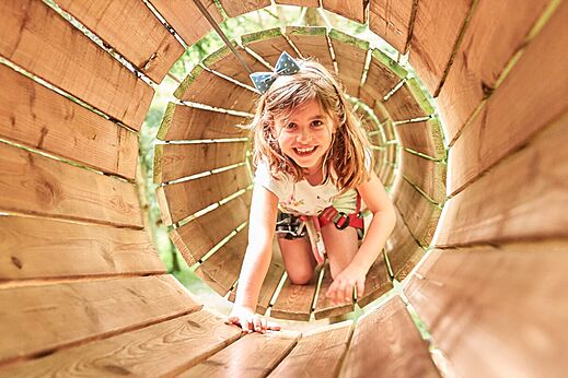 Lachend meisje in houten tunnel, avonturenparcours, camping CAPFUN Grand Cerf in Gimouille.