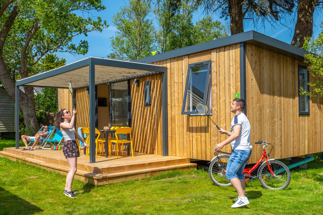 Modern stacaravan, stel speelt badminton, terras op camping CAPFUN Grand Large in FOUESNANT.