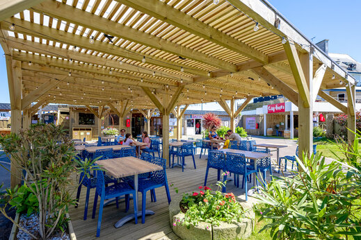 Schaduwrijk restaurantterras met gezinnen op camping CAPFUN Grand Large in FOUESNANT.