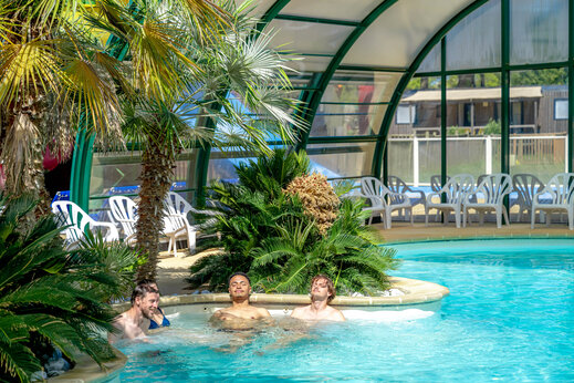 Jacuzzi en overdekt zwembad met palmbomen op camping CAPFUN Grand Large in FOUESNANT.