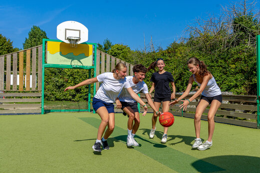 Tieners basketballen op multisportterrein op camping CAPFUN Grenouillère in Suèvres (41).