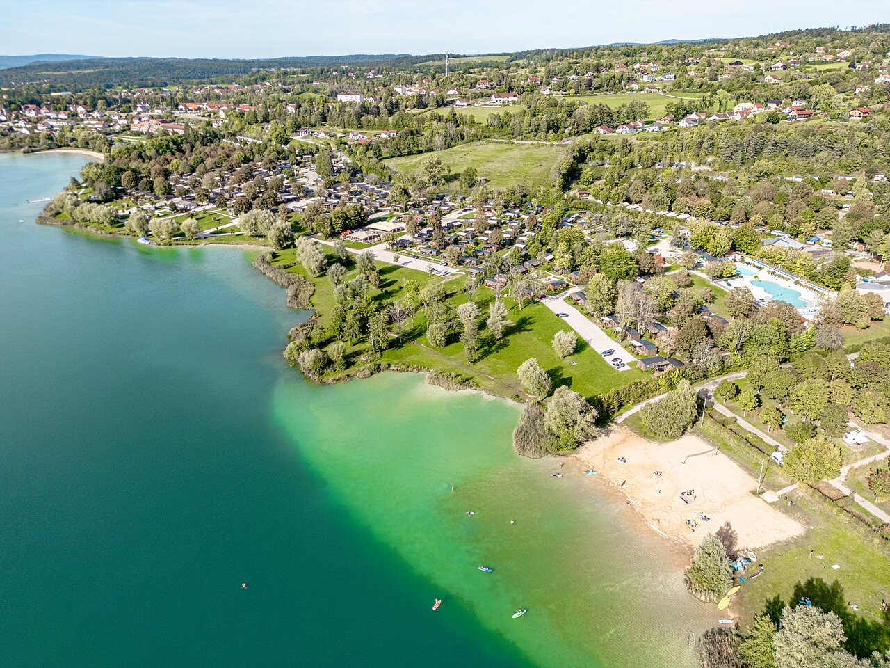 Luchtfoto meer, zandstrand en accommodaties op camping CLICOCHIC Grisi�re in Clairvaux-les-Lacs (39).