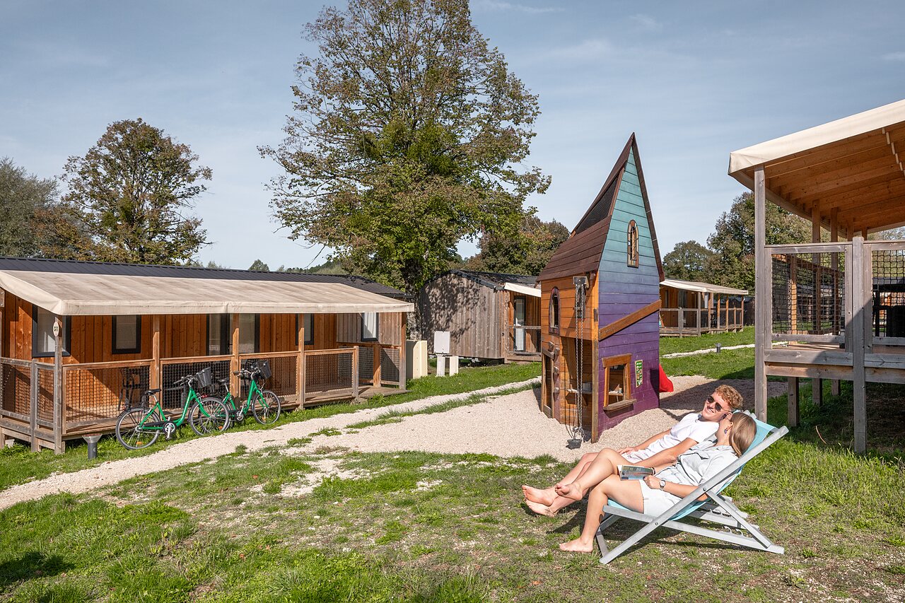 Koppel ontspant bij chalet en speeltuin op camping CLICOCHIC Grisi�re in Clairvaux-les-Lacs (39).