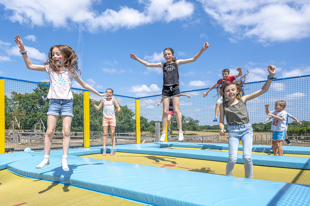 Vrolijke kinderen springen op de trampolines van de speeltuin op camping CLICOCHIC Grisi�re in Clairvaux-les-Lacs (39).