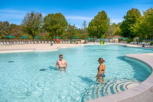 Groot buitenzwembad met stoelen en parasols op camping CLICOCHIC Grisi�re in Clairvaux-les-Lacs (39).