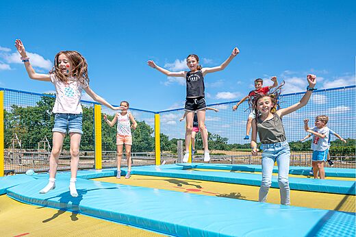 Kinderen springen vrolijk op trampolines op camping CLICOCHIC Grisière in Clairvaux-les-Lacs (39).