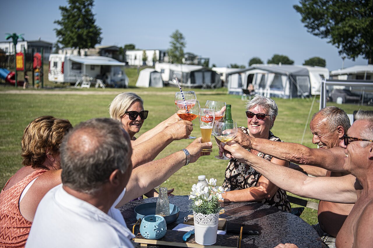 Senioren proosten vrolijk op een campingplaats bij CAPFUN Groene Eiland.