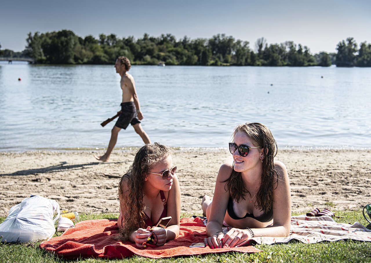 Twee jonge vrouwen ontspannen op strand bij camping CAPFUN Groene Eiland Appeltern.