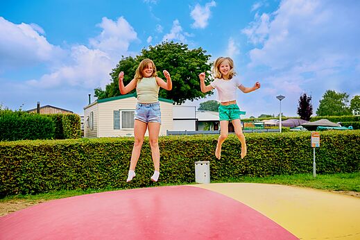 Twee kinderen springen op een reusachtig springkussen op camping CAPFUN Groene Eiland in Appeltern.