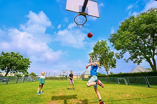 Multisportterrein met kinderen die basketballen op camping CAPFUN Groene Eiland in Appeltern.