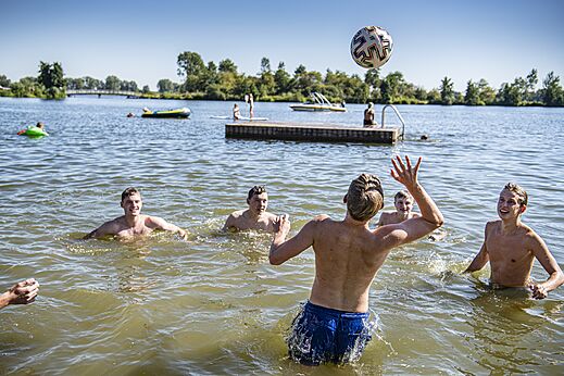 Jongeren volleyballen in het meerwater op camping CAPFUN Groene Eiland in Appeltern.