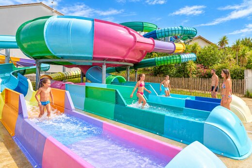 Kleurrijke waterglijbanen en kinderen op camping VAGUES OCEANES Grosses Pierres, Saint-Georges-d'Oléron (17).