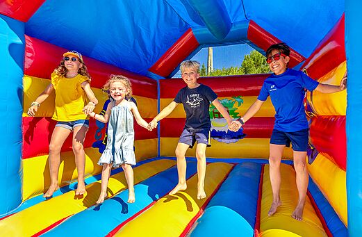 Vrolijke kinderen springen in een kleurrijk springkasteel op camping VAGUES OCEANES Grosses Pierres in Saint-Georges-d'Oléron (17).