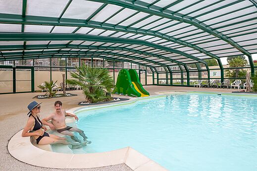 Overdekt zwembad, waterglijbaan en stel op camping CLICOCHIC Haras de Deauville.