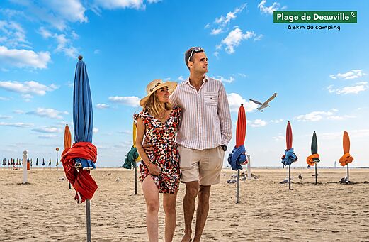 Strand van Deauville met kleurrijke parasols en stel, bezienswaardigheid in Normandië.