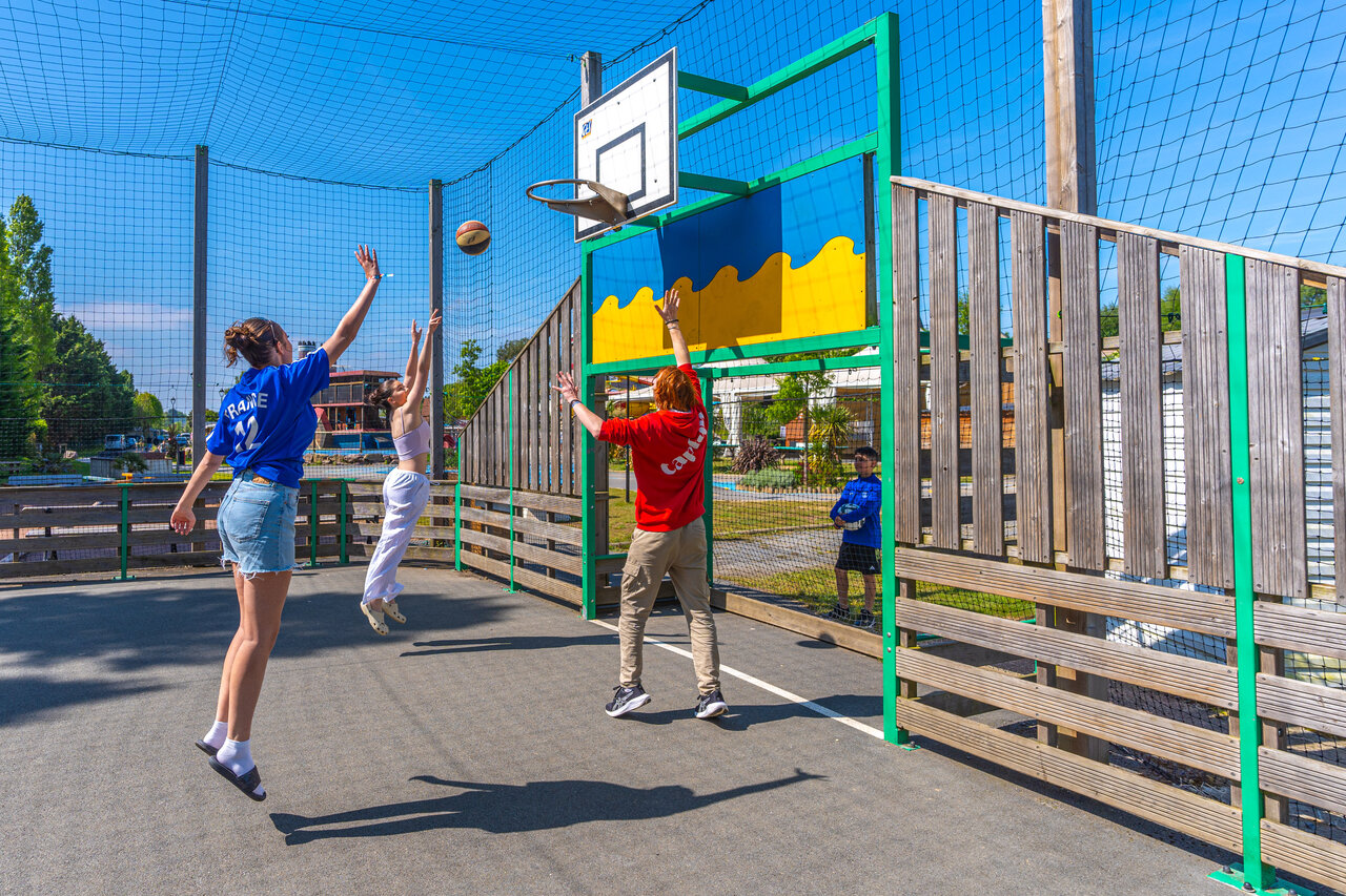 Jongeren basketballen op multisportterrein op camping CAPFUN Hautes Coutures in BENOUVILLE.