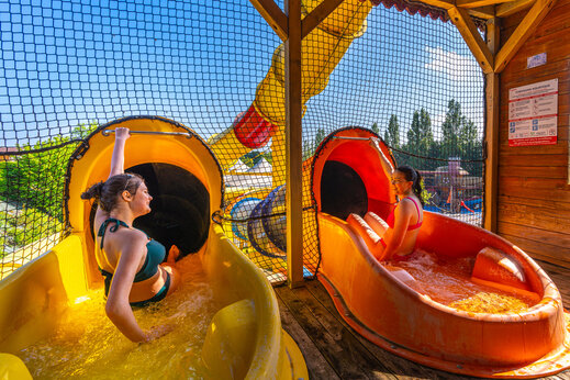 Lachende jonge vrouwen op waterglijbanen op camping CAPFUN Hautes Coutures in BENOUVILLE (14).