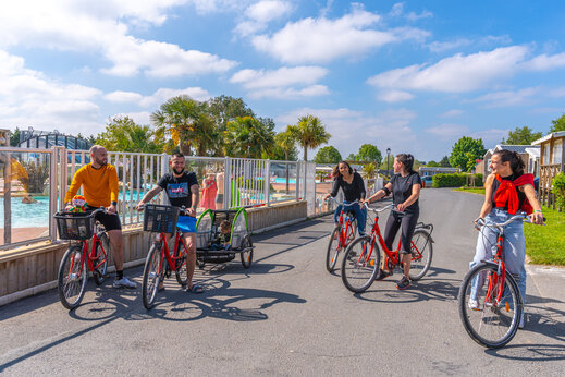 Familie op de fiets met kinderkar op camping CAPFUN Hautes Coutures in BENOUVILLE (14).