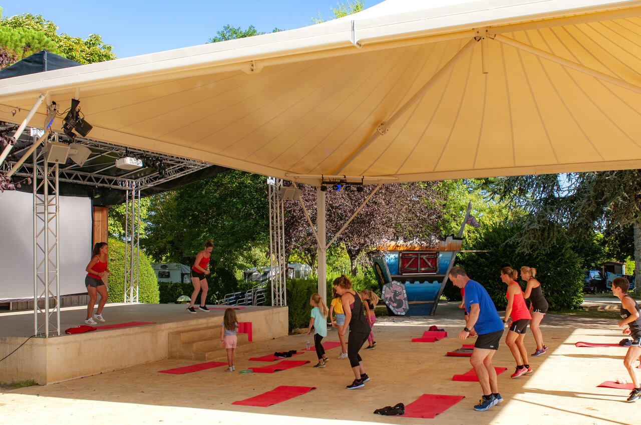 Outdoor fitnessles op overdekt podium op camping CAPFUN Hauts de Ratebout in STE FOY DE BELVES (24).