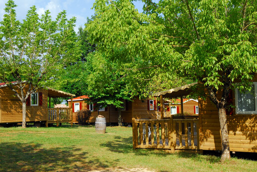 Houten stacaravans met schaduwrijke terrassen op camping CAPFUN Hauts de Ratebout in STE FOY DE BELVES (24).