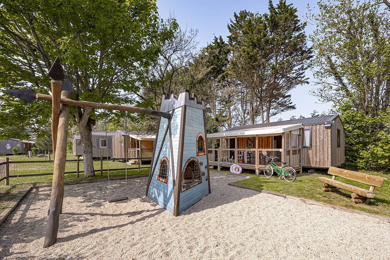 Kinderspeeltuin met kasteel en schommel, stacaravans op camping CLICOCHIC Havre de Berni�res in Berni�res-sur-Mer (14).