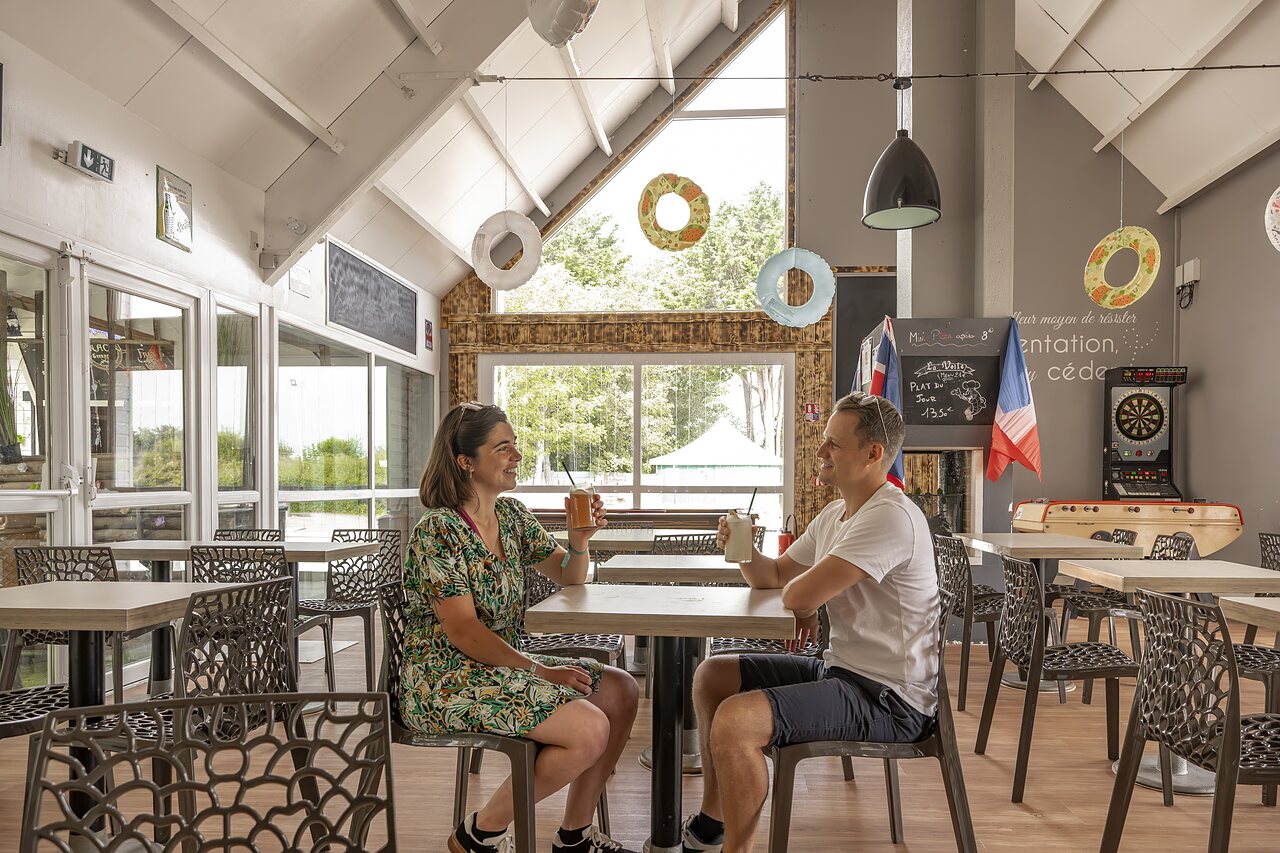 Lachend stel drinkt een drankje in de bar van camping CLICOCHIC Havre de Berni�res.