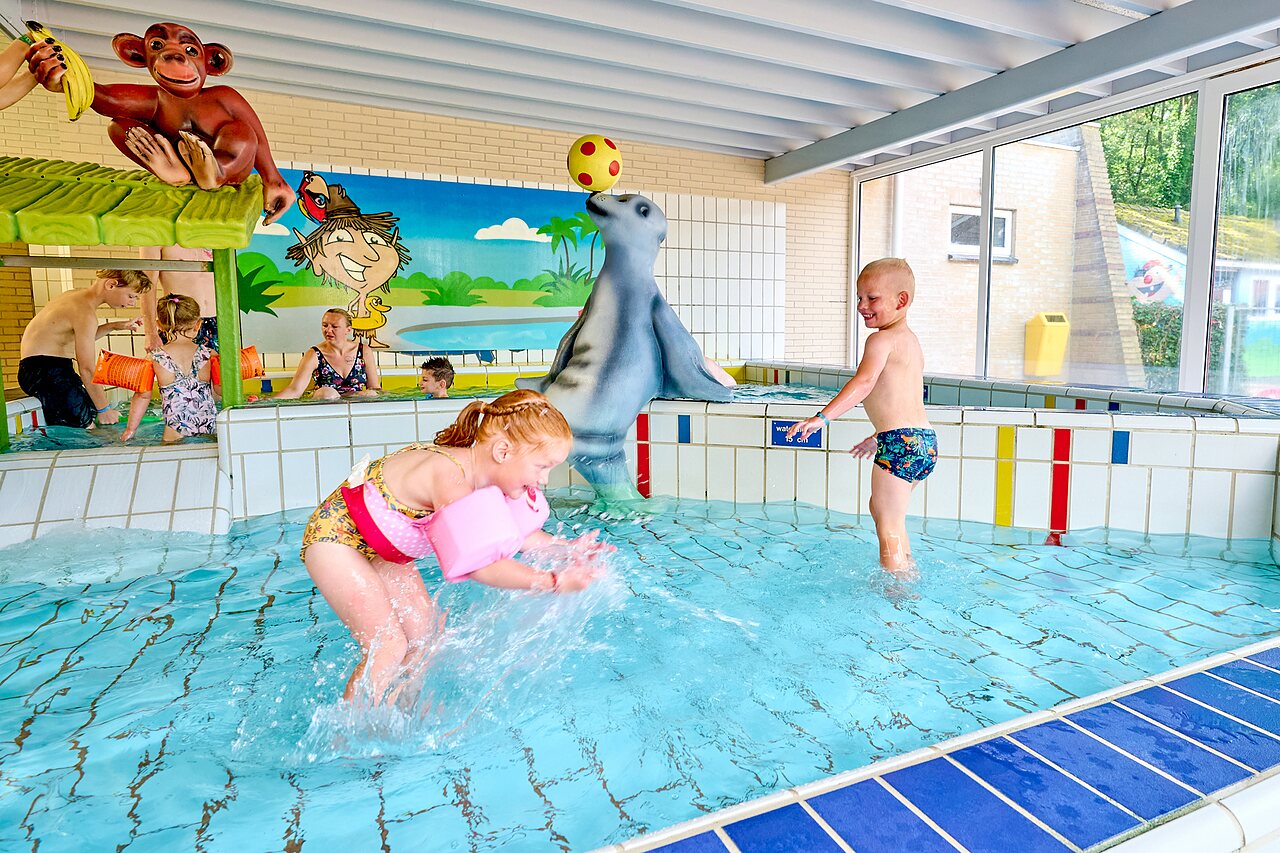 Binnenzwembad met waterspellen en kinderen op camping CAPFUN Heino in Heino.