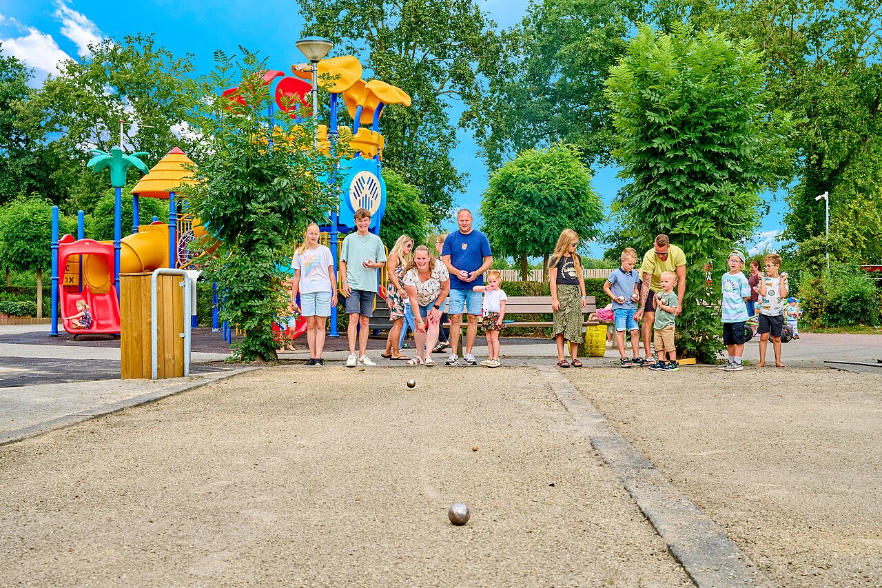 Familie speelt jeu de boules bij speeltuin op camping CAPFUN Heino in Heino.