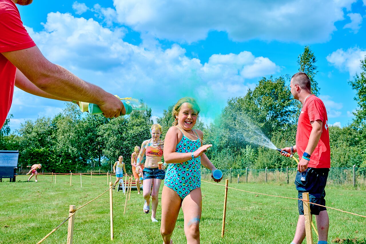 Vrolijke kinderen bij kleurenloop met waterstralen op camping CAPFUN Heino in Heino.