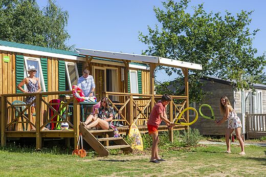 Familie genietend van een stacaravan met terras op camping CAPFUN Heino in Heino.
