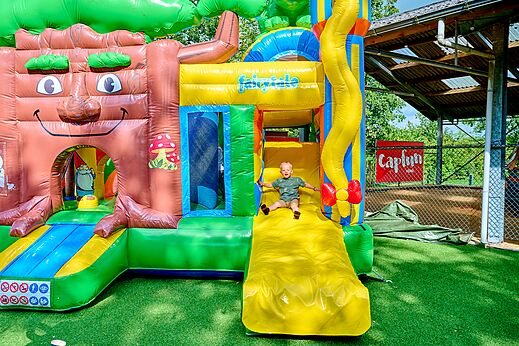 Kind op reusachtige opblaasbare structuur met glijbaan op camping CAPFUN Heino in Heino.