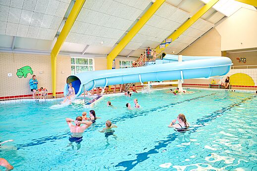Binnenzwembad met waterglijbaan en zwemmers op camping CAPFUN Heino in Heino.