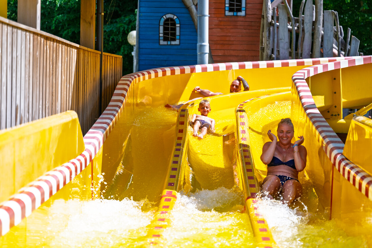 Familie plezier makend op de gele waterglijbaan op camping CAPFUN Hirondelle in Oteppe.