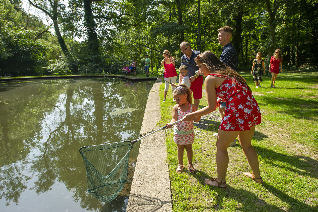 Familie vist met schepnet aan vijverrand op camping CAPFUN Hirondelle in Oteppe.