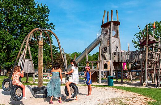Grote houten speeltuin met glijbaan en schommels op camping CAPFUN Hirondelle in Oteppe.