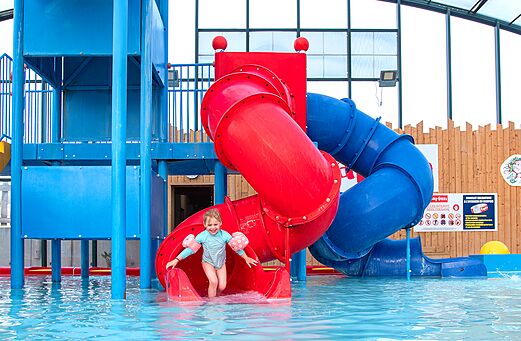 Waterglijbaan en zwembad met lachend kind op camping CAPFUN Hirondelle in Oteppe.