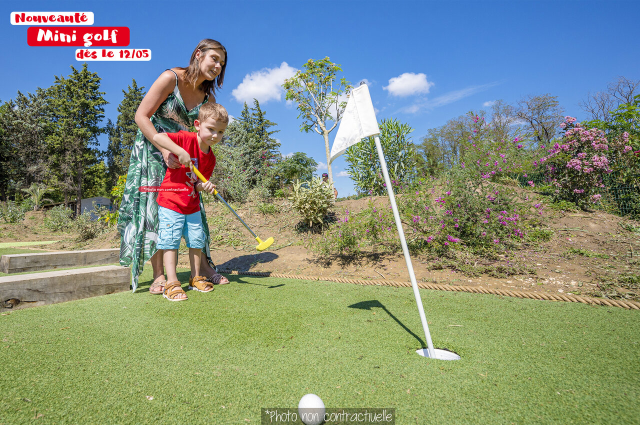 Kind en vrouw spelen minigolf op camping CAPFUN Huttes in Saint-Denis d'Ol�ron.