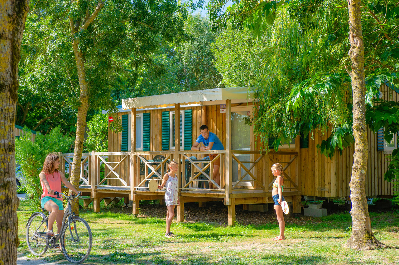 Houten stacaravan met terras, familie en fiets op camping CAPFUN Huttes in Saint-Denis d'Ol�ron (17).